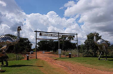 Tor mit Aufschrift "Parque Nacional das Emas", daneben auf beiden Seiten silberne Nandu-Statuen