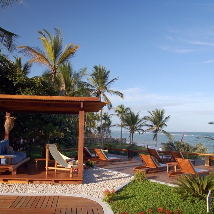 Entspannungsbereich der Pousada Pitinga in Porto Seguro, Brasilien, mit Sonnenliegen und einem Pavillon mit Blick auf das Meer.