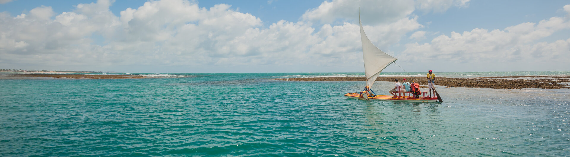 Traditionelles Jangada-Segelboot mit Passagieren auf dem türkisfarbenen Meer vor Porto de Galinhas in Brasilien.