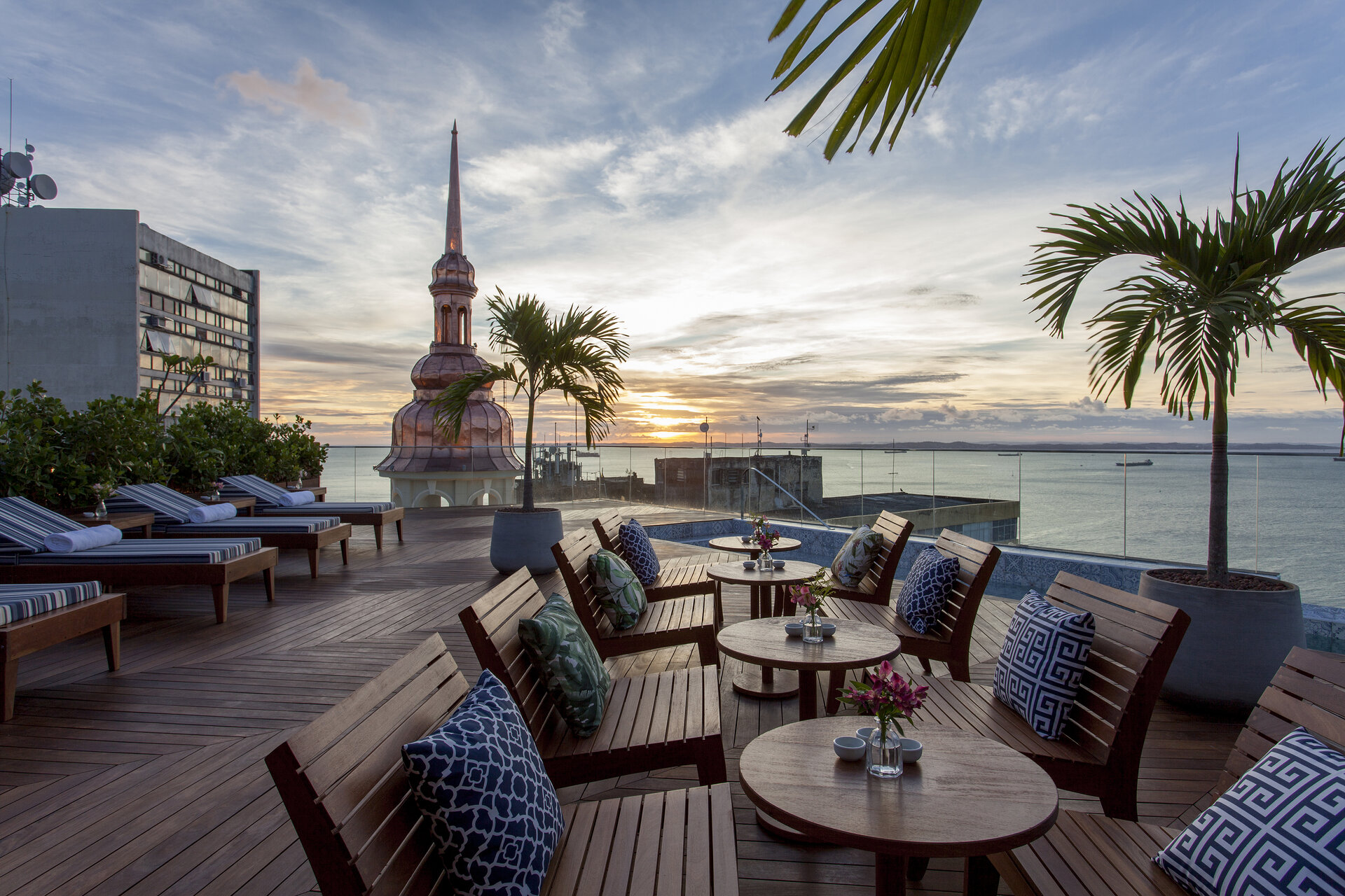 Fera Palace Hotel Dachterrasse mit Holzliegen und Blick auf die Allerheiligenbucht bei Sonnenuntergang in Salvador.