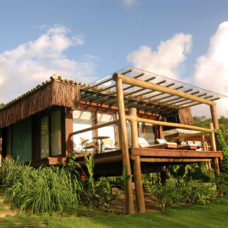 Luxusbungalow aus Holz mit Sonnenterrasse und Glasdach auf gepflegtem Rasen im Txai Resort, Itacaré, Brasilien.