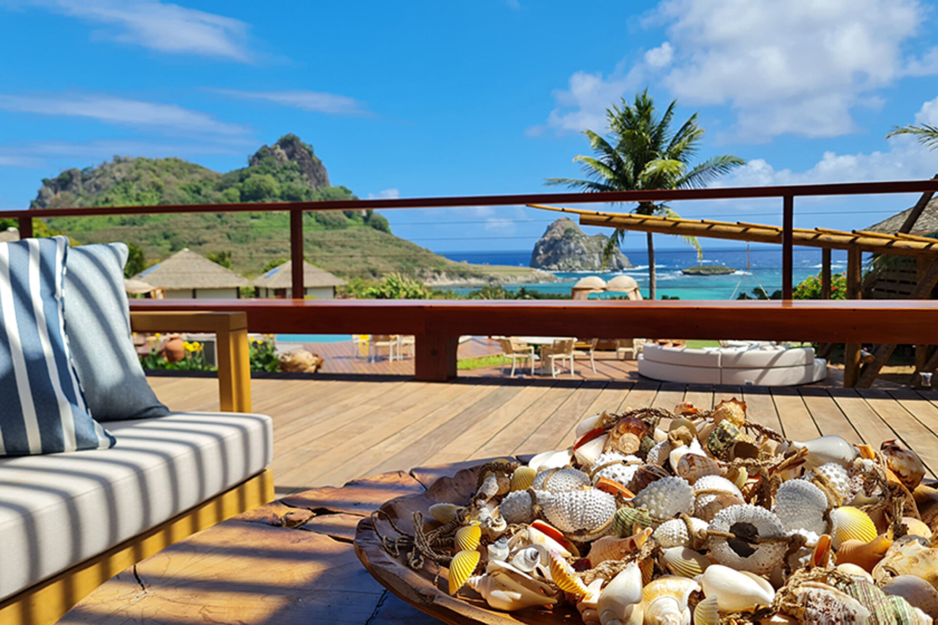 Balkon der Pousada Solar dos Ventos auf Fernando de Noronha mit Muscheldekoration und Blick auf das Meer und Hügel.