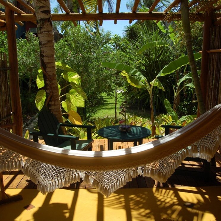 Veranda der Pousada Pitinga in Porto Seguro, Brasilien, mit gemütlicher Hängematte und Blick auf den üppigen tropischen Garten.
