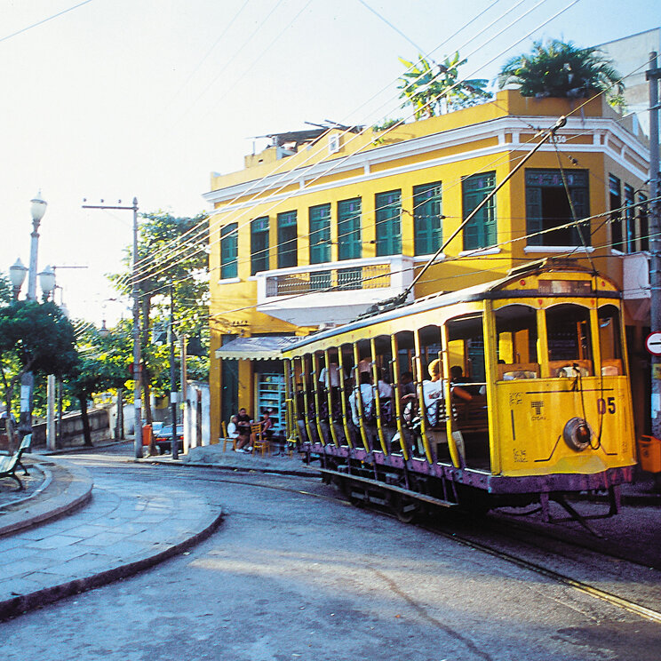 Bunter Straßenbahnwagen in einem historischen Viertel von Rio de Janeiro, umgeben von historischen Gebäuden.