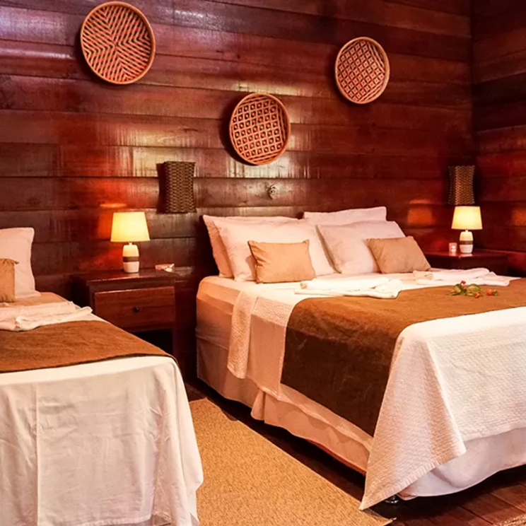 Zimmer in der Manati Lodge im Amazonas, Brasilien, mit rustikalem Holzdesign und zwei Betten.