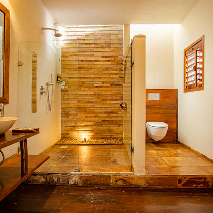 Badezimmer der Suite Jardim mit Steindusche, Holzwaschtisch und separatem WC im Hotel in Jericoacoara.