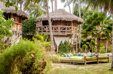Vila Kalango Jericoacoara: Palafitas aus Holz im Palmengarten mit Außenlounge und bunten Kissen in Brasilien.