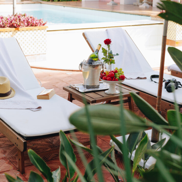Sonnenliegen mit Hut, Buch und Champagner am Pool des Boutique-Hotels in Florianopolis, Brasilien.