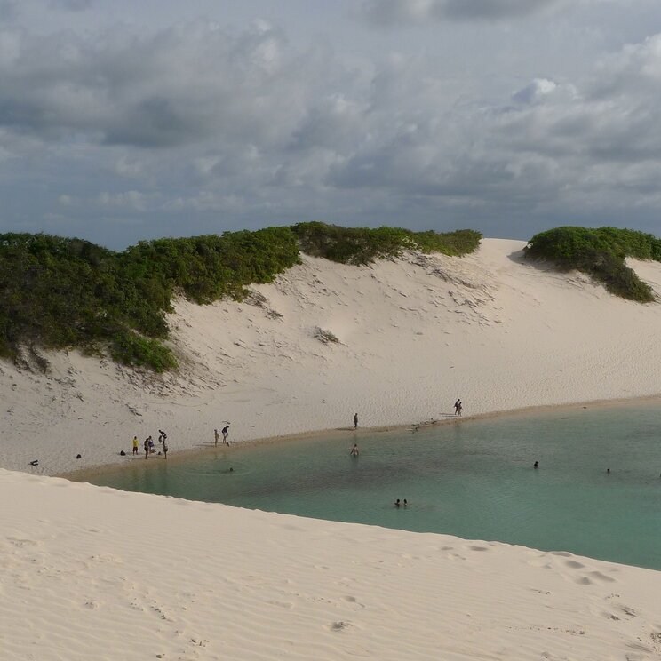 Atemberaubende Ansicht der Sanddünen und Wasserlagunen im Lençóis Maranhenses, Brasilien, unter einem dramatischen Himmel mit Wolken, die die Landschaft in sanften Farben beleuchten.