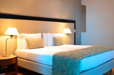 King-Size-Bett mit hellem Kopfteil und zwei Nachttischlampen im Hotel Pestana Sao Paulo, Brasilien.