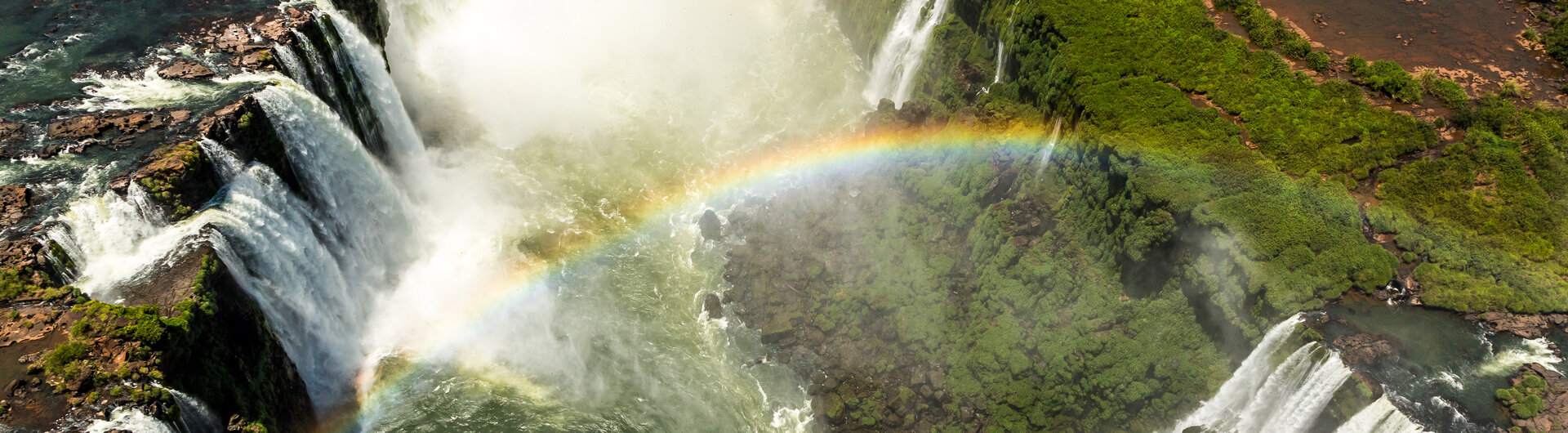 Luftaufnahme der Iguazú-Wasserfälle mit einem leuchtenden Regenbogen über den Kaskaden in Foz do Iguaçu, Brasilien.