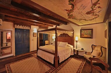 Suite mit dunklem Holz-Himmelbett und kunstvoll bemalter Decke in der Pousada do Amparo in Olinda.