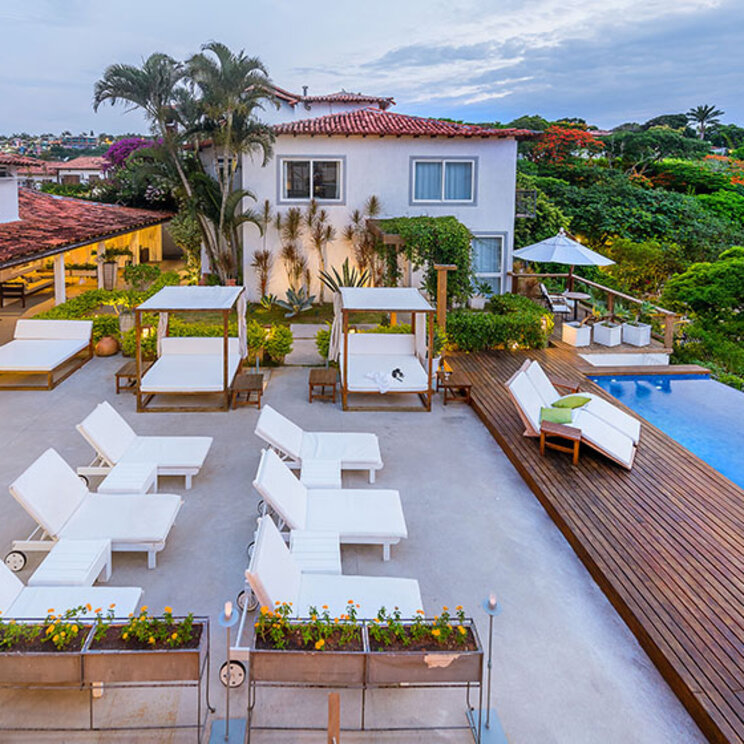 Außenanlage der Pousada Abracadabra in Brasilien mit Pool, Sonnenliegen, Daybeds und weißen Hotelgebäuden.