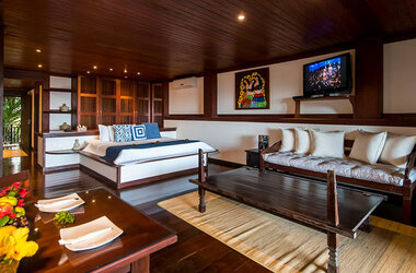 Geräumige Suite mit dunklem Holzboden, Sitzbereich, Fernseher und Kingsize-Bett.