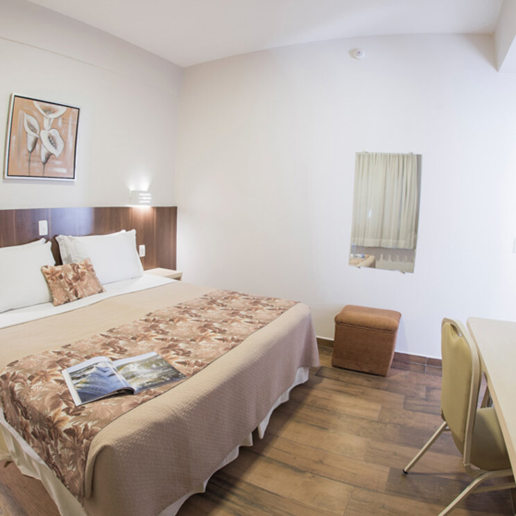 Standard-Doppelzimmer im Hotel Taroba mit Holzboden, Schreibtisch und Wandgemälde über dem Kopfteil des Bettes.