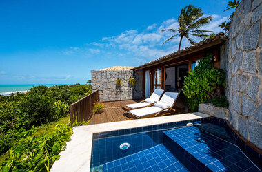 Holzterrasse mit zwei Sonnenliegen und privatem Infinity-Pool vor der Küste von Natal.
