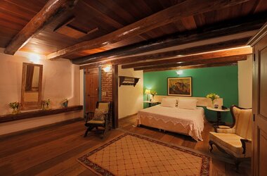 Geräumiges Gästezimmer mit Holzbalkendecke, Parkettboden und grüner Akzentwand in Olinda, Brasilien.