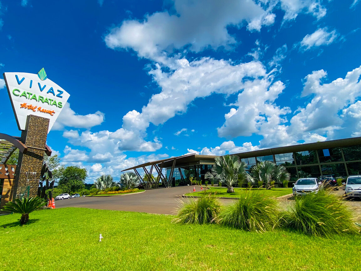 Vivaz Cataratas Hotel Resort in Foz do Iguacu Brasilien mit Einfahrt, Palmen, Logo-Schild und blauem Himmel.