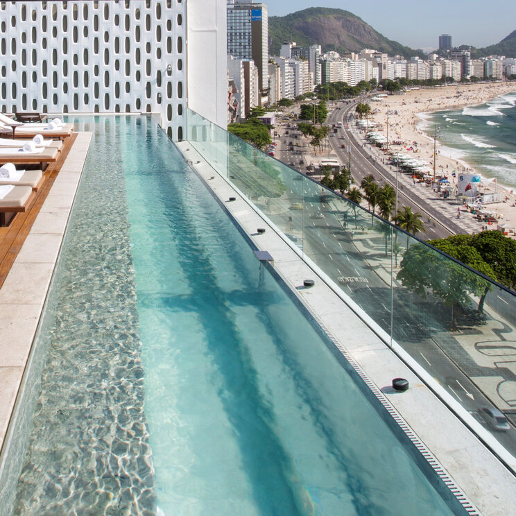 Blick entlang des Infinity-Pools auf dem Dach des Emiliano Rio auf die Küstenstraße und den Strand von Rio de Janeiro.