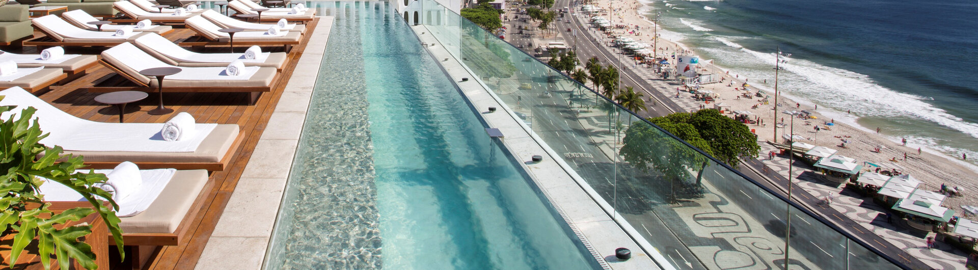 Blick entlang des Infinity-Pools auf dem Dach des Emiliano Rio auf die Küstenstraße und den Strand von Rio de Janeiro.