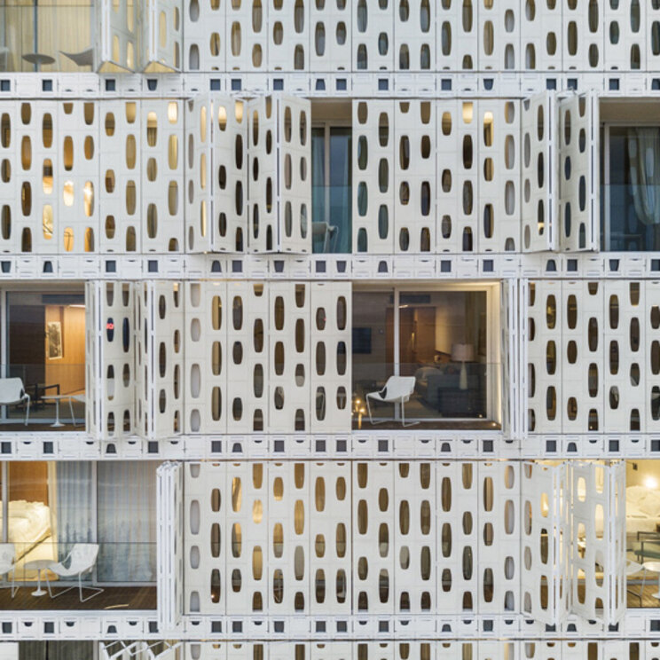 Detailansicht der weißen, strukturierten Fassade des Emiliano Rio mit geöffneten Paneelen und Hotelbalkonen in Brasilien