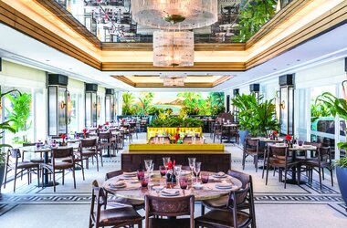 Elegantes Restaurant mit Wandgemaelde, gelben Polsterbaenken und runden Tischen in Rio de Janeiro, Brasilien.