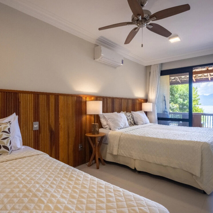 Helles Schlafzimmer mit Doppelbett, Einzelbett und Blick auf das Meer in der Pousada Naturalia, Brasilien.