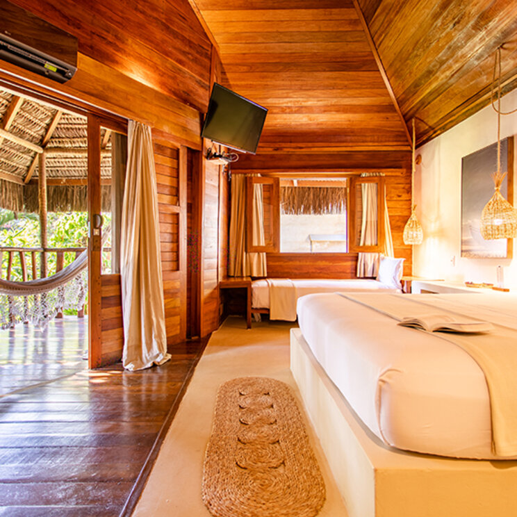 Schlafzimmer der Suite Deluxe mit Holzwaenden, Doppelbett und Balkonzugang im Hurricane Jeri in Jericoacoara.