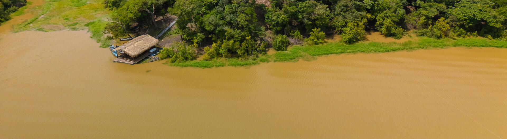 Luftaufnahme der Lodge im dichten, grünen Regenwald am Ufer eines Flusses bei Manaus.