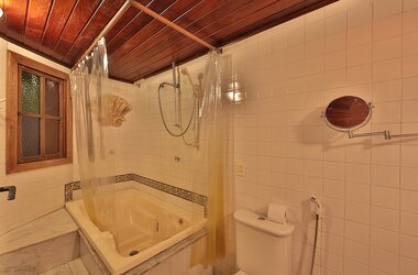 Badezimmer mit Whirlpool-Badewanne, weißen Fliesen und Holzdecke in der Pousada do Amparo, Olinda.