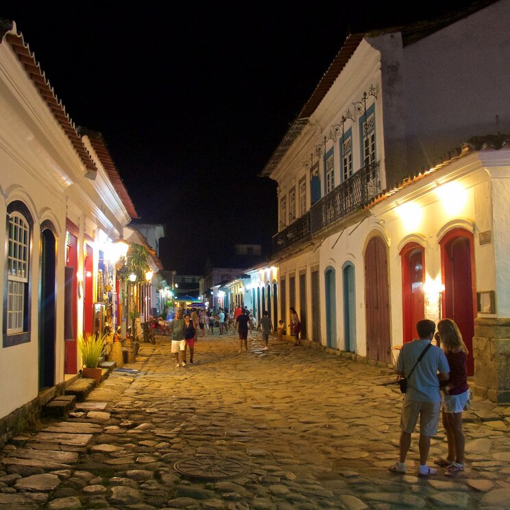 Bunte Geschäfte und Cafés in Paraty, Brasilien, mit beleuchteten Fassaden, die die koloniale Architektur der Stadt widerspiegelt.
