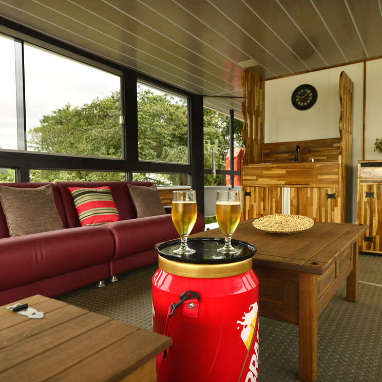 Loungebereich der Mutum Expeditions Lodge im Pantanal mit Sofa, Holzmöbeln, Barbereich und Blick ins Grüne