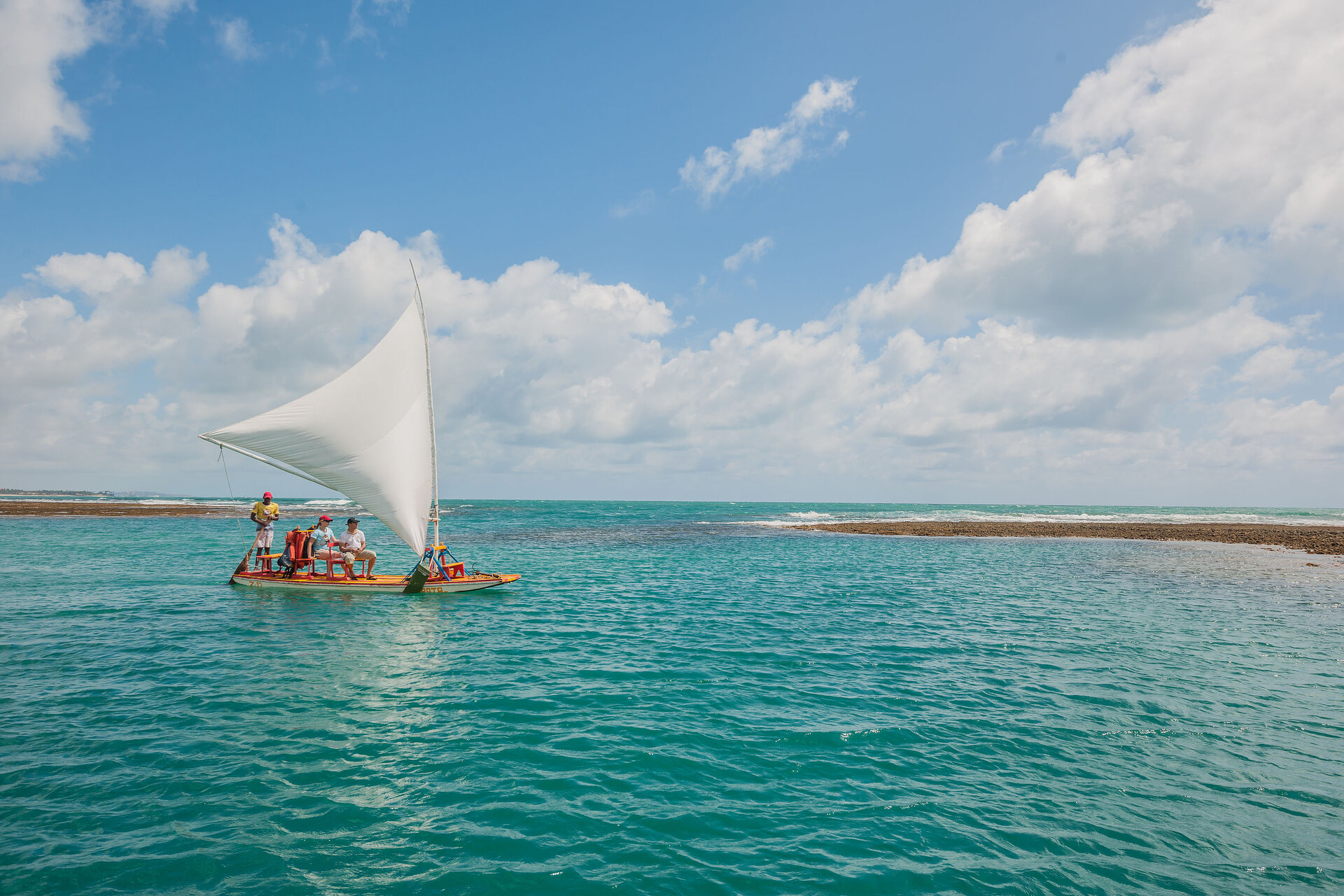 Traditionelles Segelboot mit Touristen in den türkisfarbenen Gewässern vor Porto de Galinhas, Brasilien.