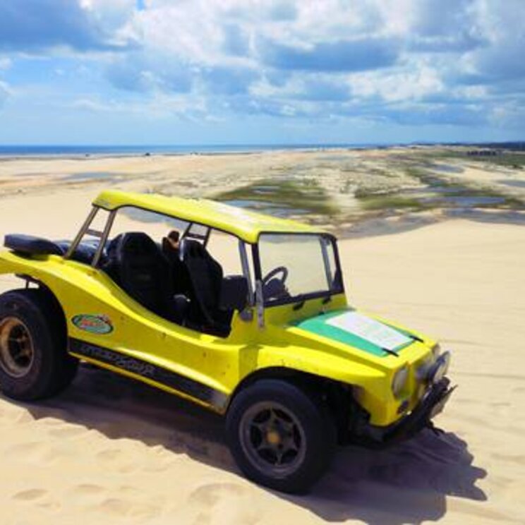 Ein gelber Buggy auf den Sanddünen von Tatajuba, mit Blick auf die weitläufige Landschaft des Lençóis Maranhenses und den klaren Himmel im Hintergrund.