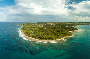 Luftaufnahme der Halbinsel Ponta do Mutá mit dichtem Palmenwald, weißem Sandstrand und türkisfarbenem Meer in Bahia.