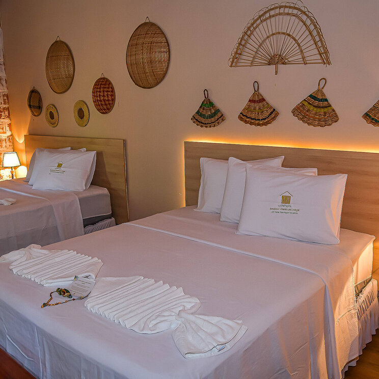 Zimmer in der Amazon Premium Lodge im Amazonas, Brasilien, mit traditionellen Wanddekorationen und gemütlicher Beleuchtung.