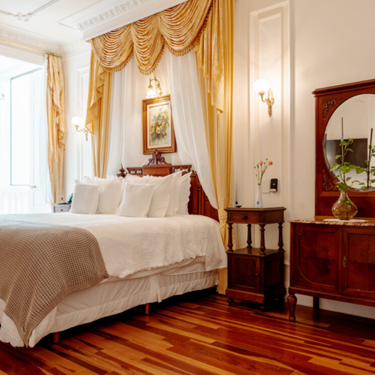 Klassisches Hotelzimmer mit Massivholzmöbeln, Parkett und gelben Vorhängen in Florianopolis.
