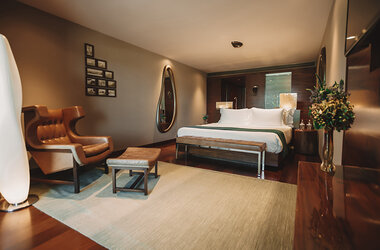 Deluxe Doppelzimmer im Hotel Fasano mit Ledersessel, Teppich und indirekter Beleuchtung in Rio de Janeiro.