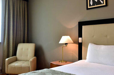 Detailansicht eines Hotelzimmers im Pestana Sao Paulo mit Einzelbett, Nachttischlampe und Sessel in Brasilien.