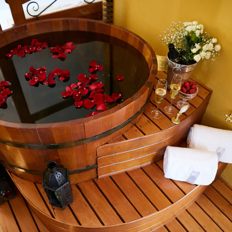 Runde Holzbadewanne mit Rosenblüten, Champagner und frischen Blumen im Hotel in Florianopolis.