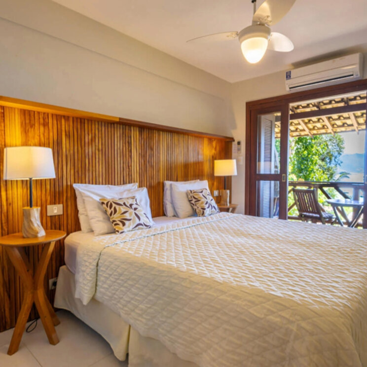 Doppelzimmer mit Holzpaneelen an der Wand und Balkon mit Meerblick in der Pousada Naturalia, Ilha Grande.