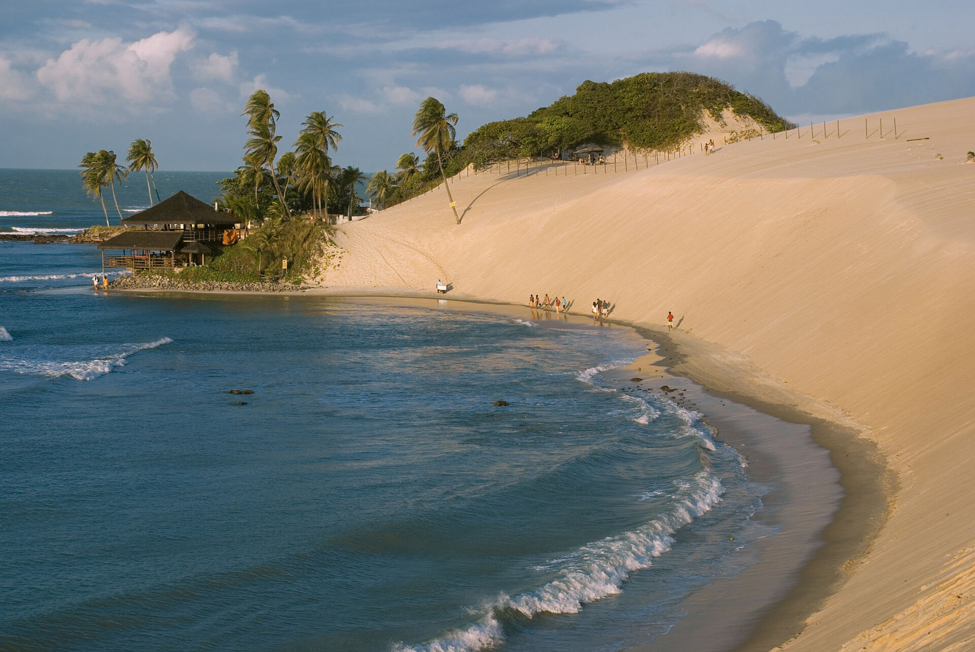 Der atemberaubende Sandstrand von Genipabu in Natal, Brasilien, mit seinen charakteristischen hohen Dünen und Palmen, die sich ideal für Abenteueraktivitäten wie Sandboarding eignen.