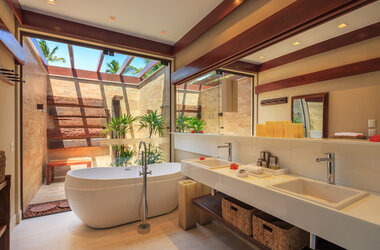 Helles Badezimmer mit Badewanne und Blick in einen kleinen privaten Innengarten im Nannai Resort.