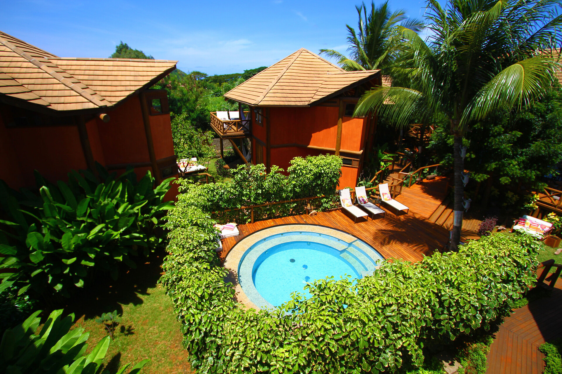 Außenansicht des Hotels Pousada Triboju in Fernando de Noronha, mit einem einladenden, runden Pool, umgeben von tropischer Vegetation und entspannenden Liegeflächen.