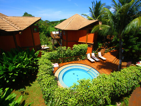 Außenansicht des Hotels Pousada Triboju in Fernando de Noronha, mit einem einladenden, runden Pool, umgeben von tropischer Vegetation und entspannenden Liegeflächen.