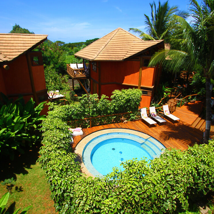 Außenansicht des Hotels Pousada Triboju in Fernando de Noronha, mit einem einladenden, runden Pool, umgeben von tropischer Vegetation und entspannenden Liegeflächen.