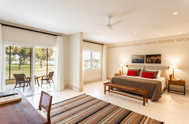 Refúgio Ecológico Caiman: Helle Superior Suite mit King-Size-Bett, buntem Teppich und Terrasse im Pantanal.