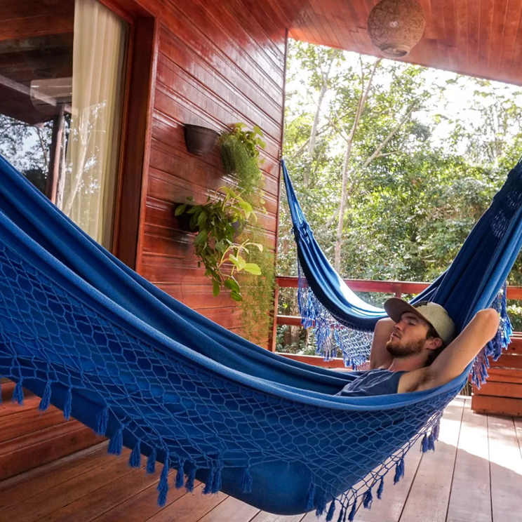Gast in einer Hängematte in der Manati Lodge im Amazonas, Brasilien, umgeben von üppiger Vegetation.