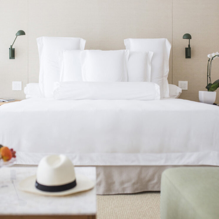 Helles Hotelzimmer im Emiliano Rio mit weißem Bett, Obstteller und Blick auf ein modernes Interieur in Rio de Janeiro.