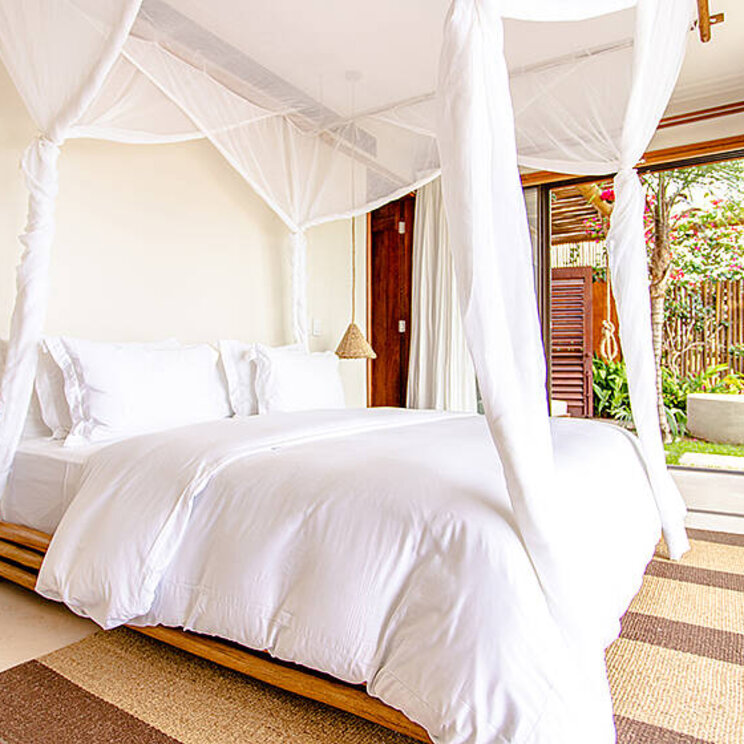 Zimmer in der Deluxe Suite des Hotel Villa Mandi in Jericoacoara, Brasilien, mit direktem Zugang zur Terrasse und Blick auf den Garten.
